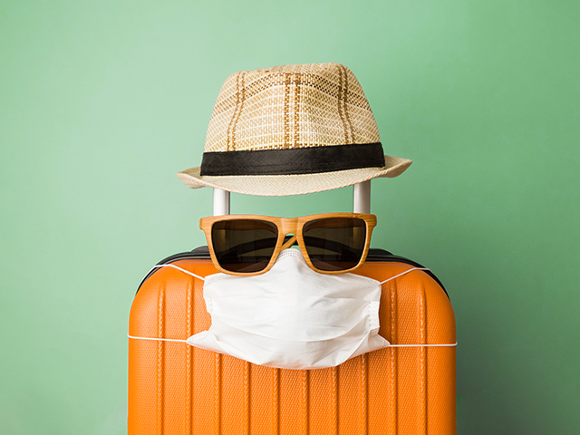 Suitcase with sunglasses, a hat, and a covid masks